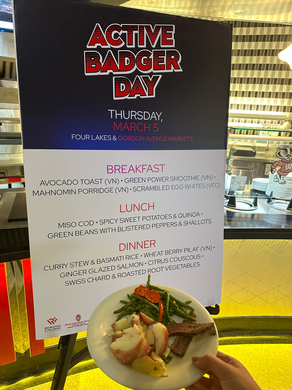 Active Badger Day plated lunch with large sign at Four Lakes Market