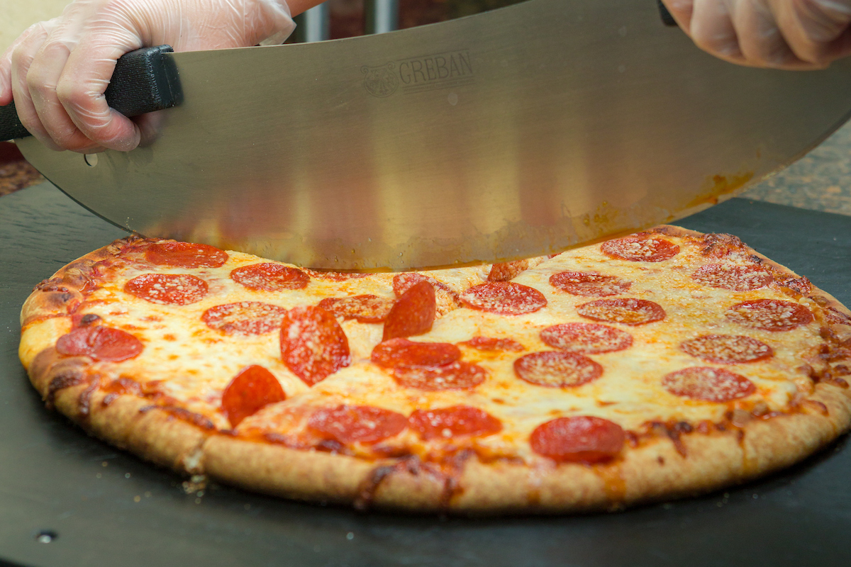 Pizza being sliced by pizza cutter