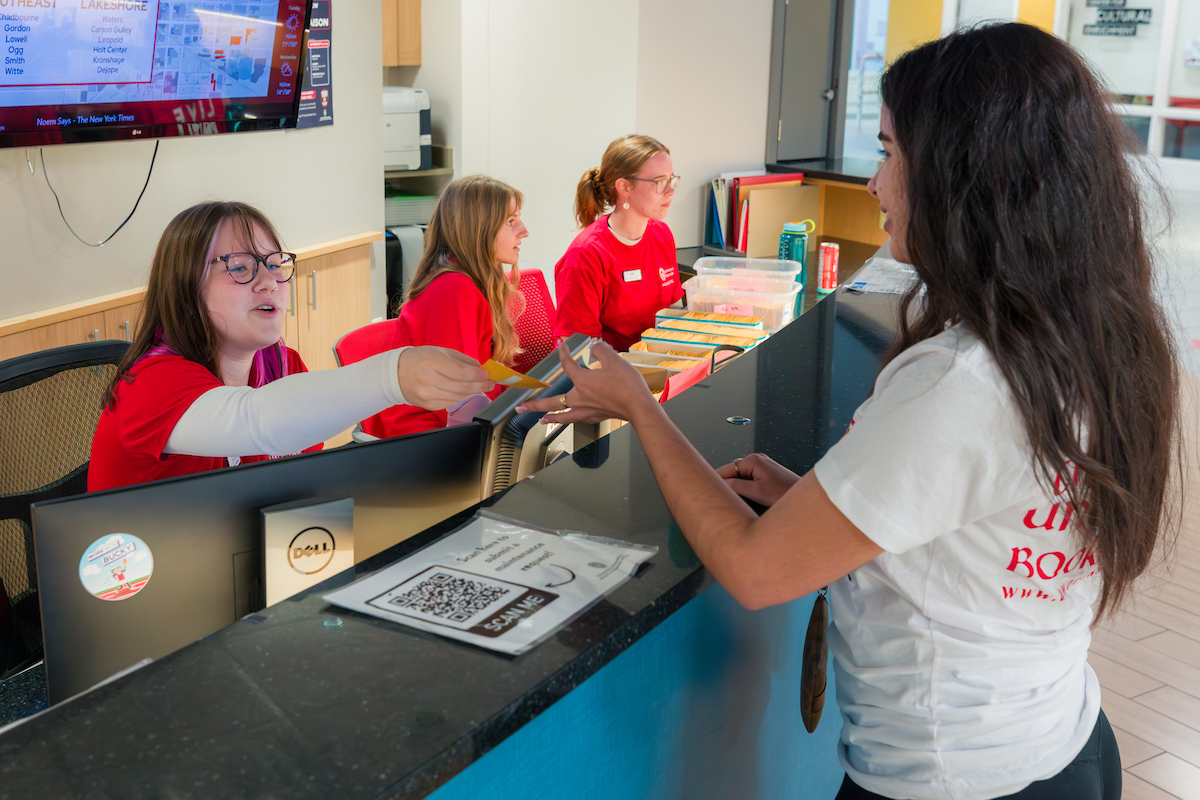 Student receiving keys on move-in day from residence hall front desk worker.