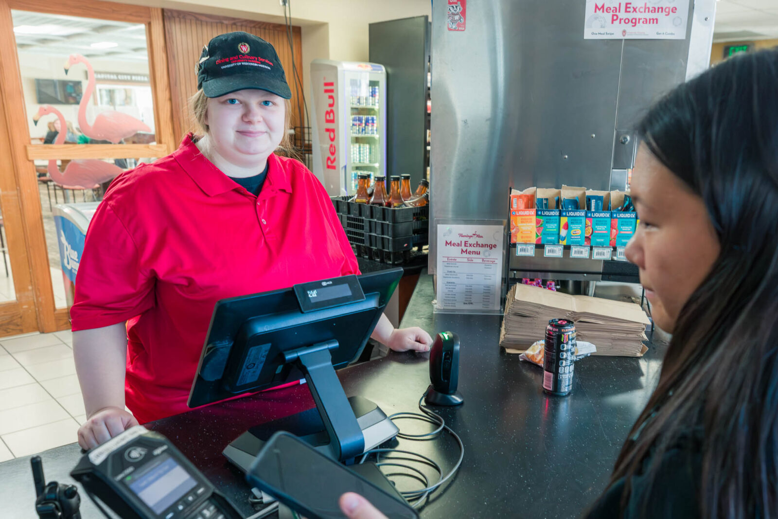 Jaedyn helps a customer check out in the Flamingo Run at Rheta's Market in Chadbourne Residence Hall.