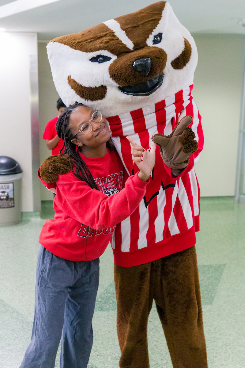 Bucky Badger and a student posing together with the "W" hand pose.