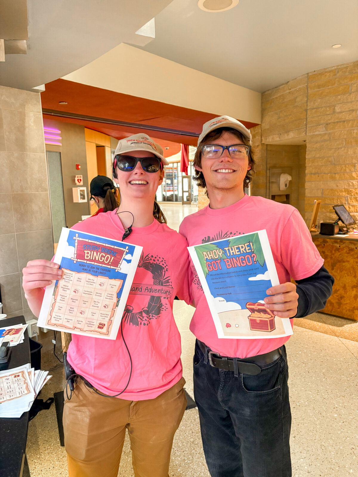 Student staff pose for photo with bingo cards and matching pink shirts at Bucky's Send Off Dinner