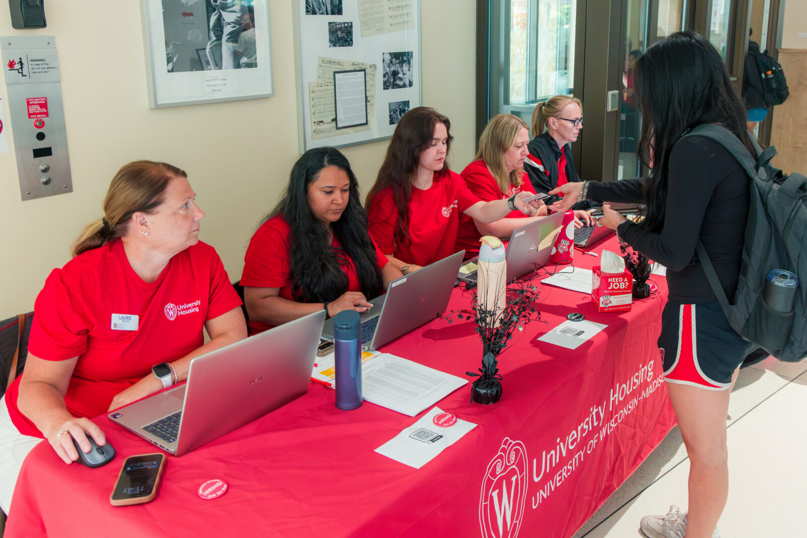 Five Human Resources staff sit at a table while a person hands them an ID card