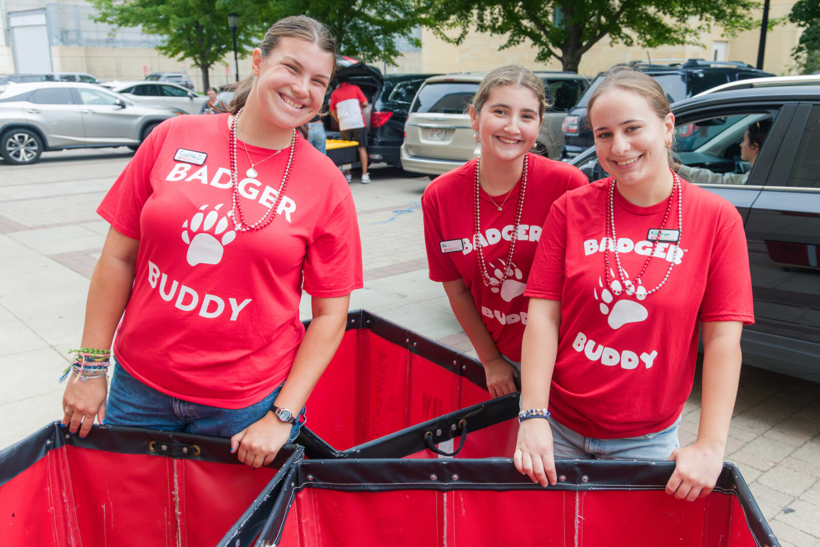 Three Badger Buddies pose behind red moving carts