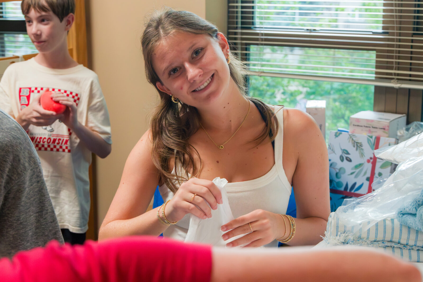 A student smiles at the camera while unpacking in their room