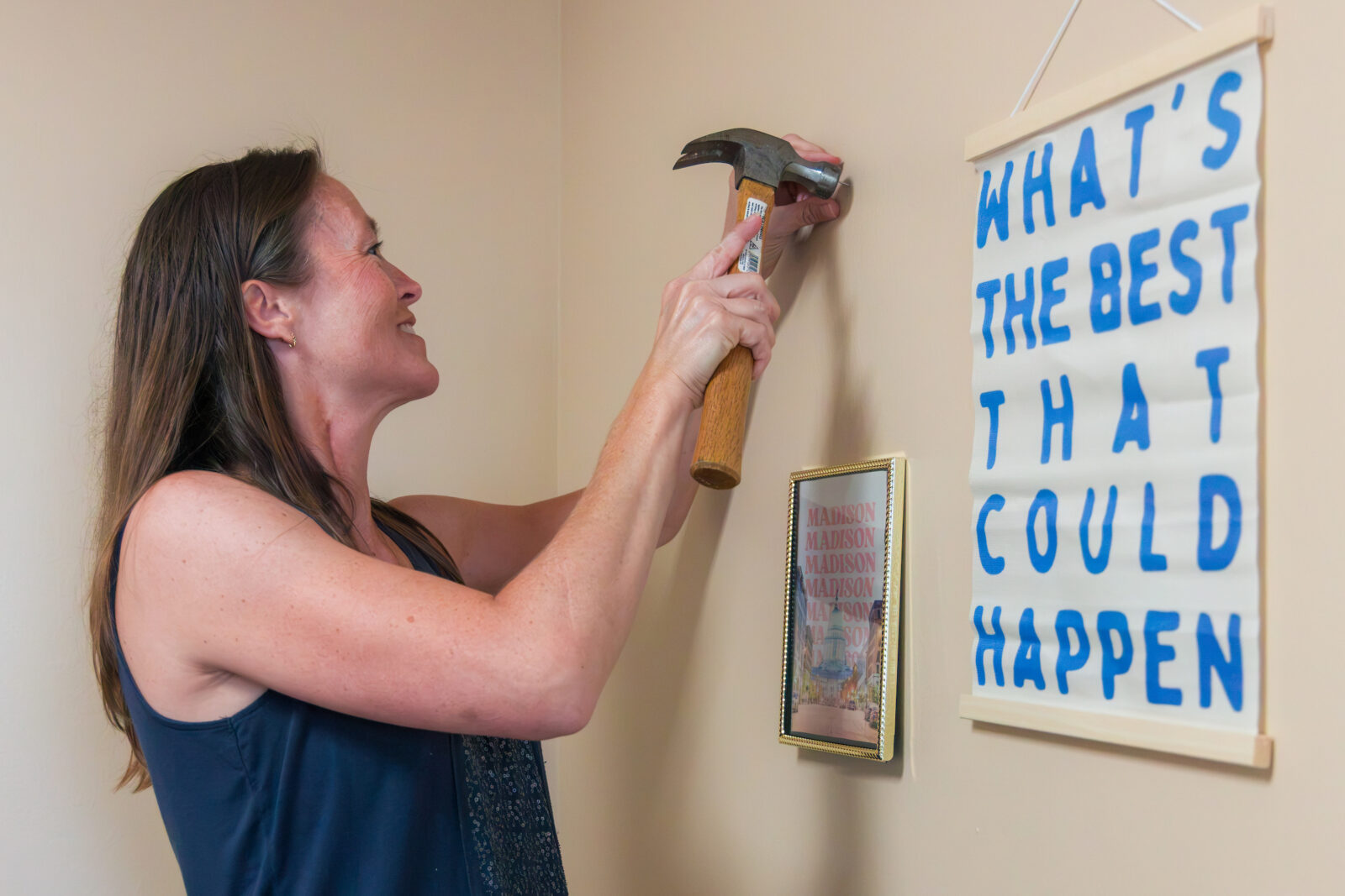 A person hammering a nail into a wall with a sign that reads "What's the best that could happen" in the foreground