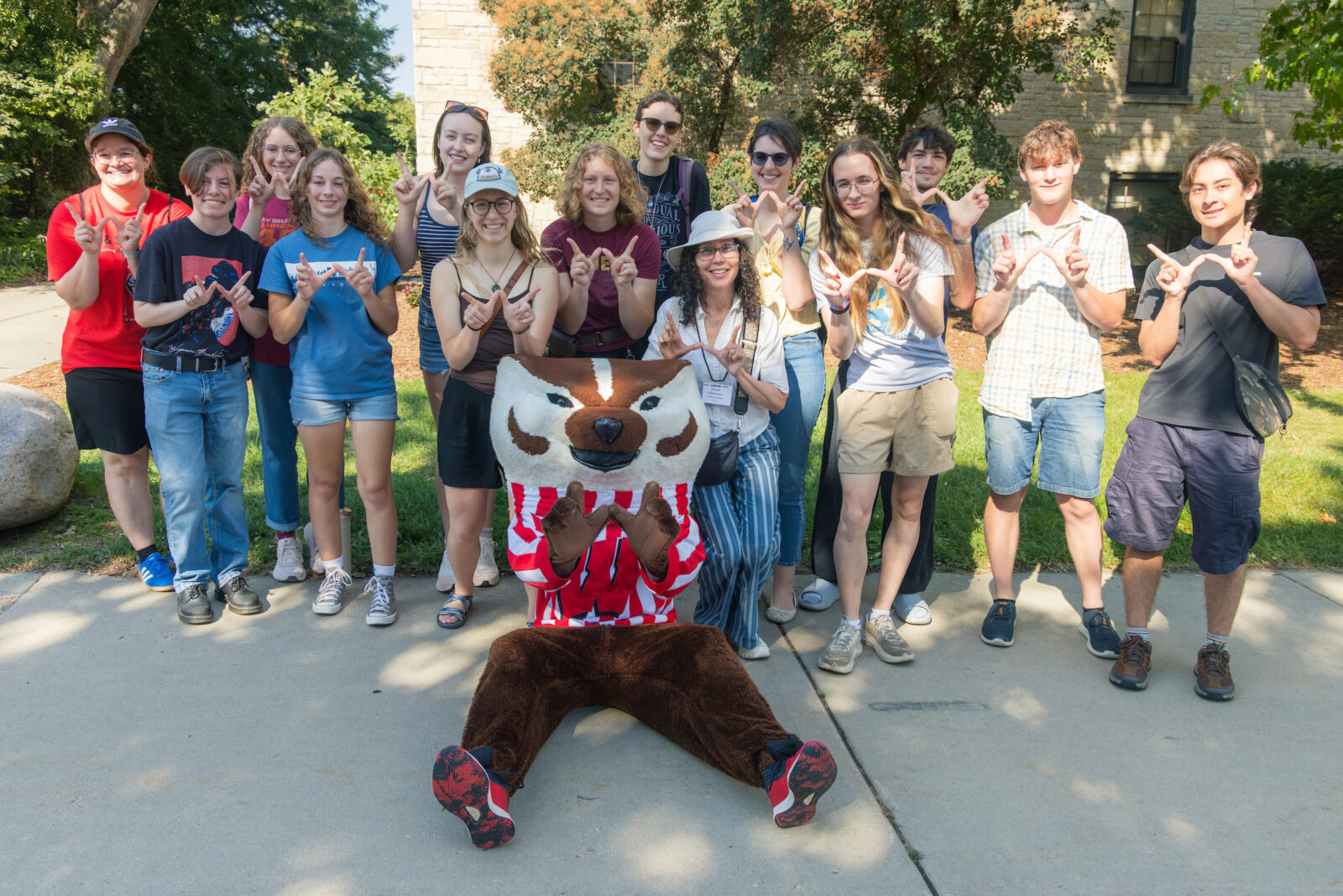 Bucky Badger poses with a large group of people while they all make the letter "W" with their hands