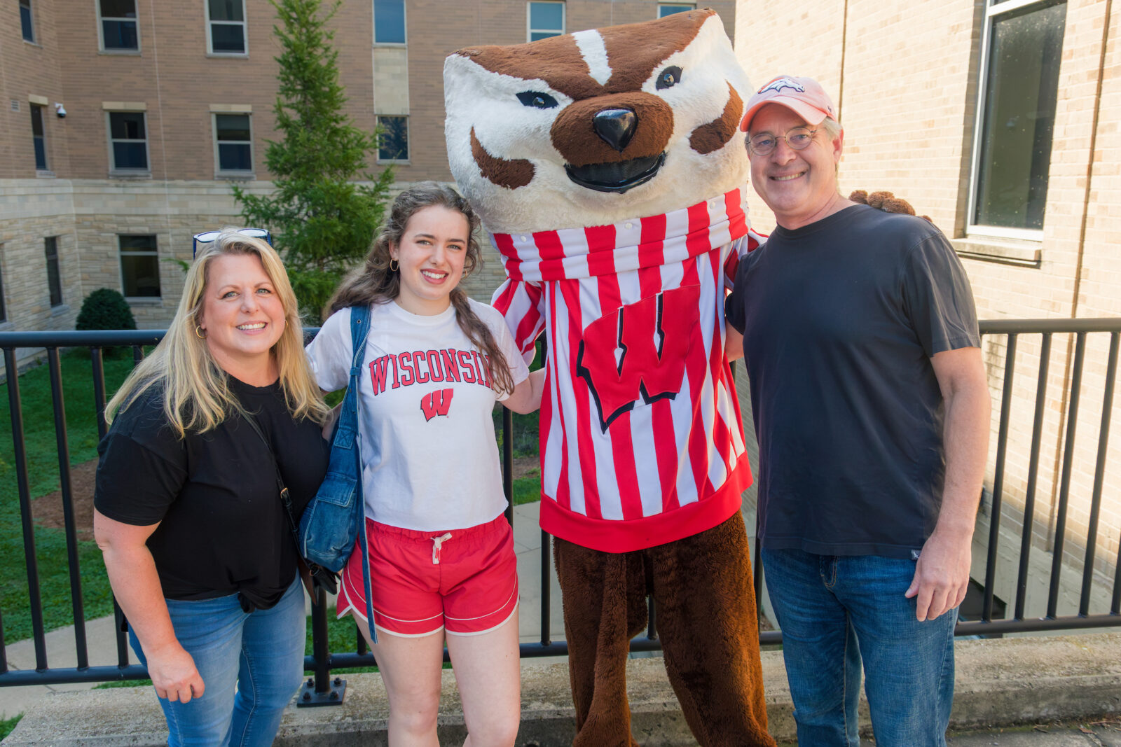 Bucky Badger poses with a student and their parents