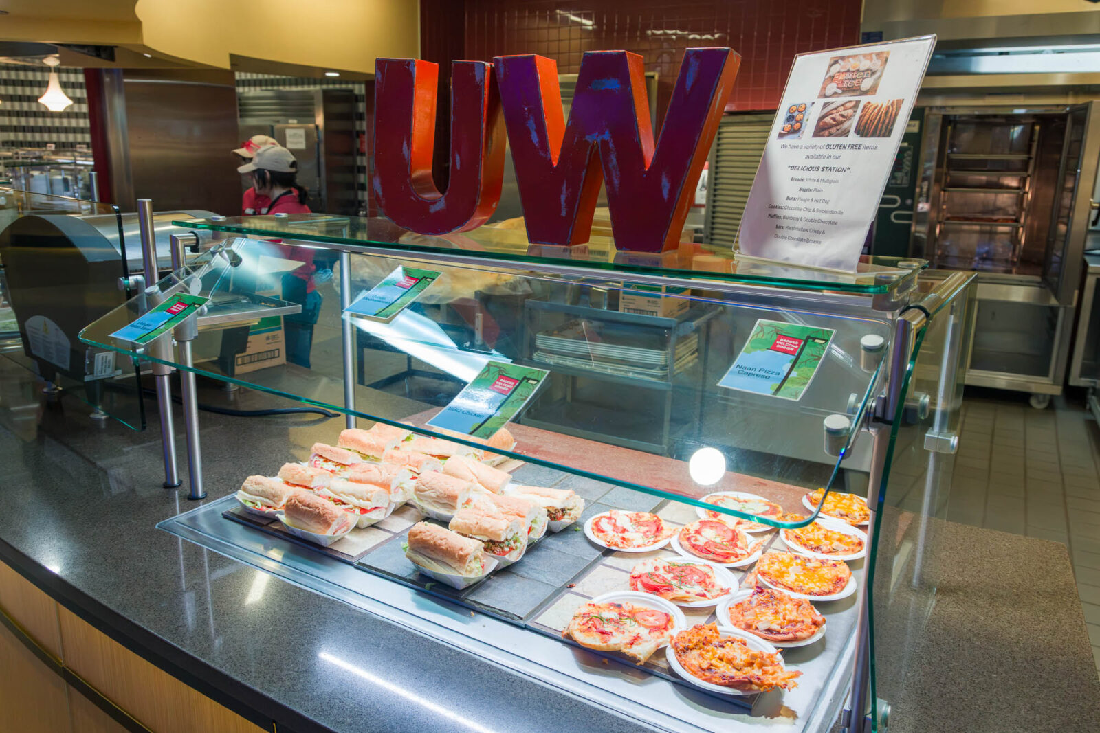 Food is pictured at the Delicious station at Four Lakes Market with large letters reading 'UW" above