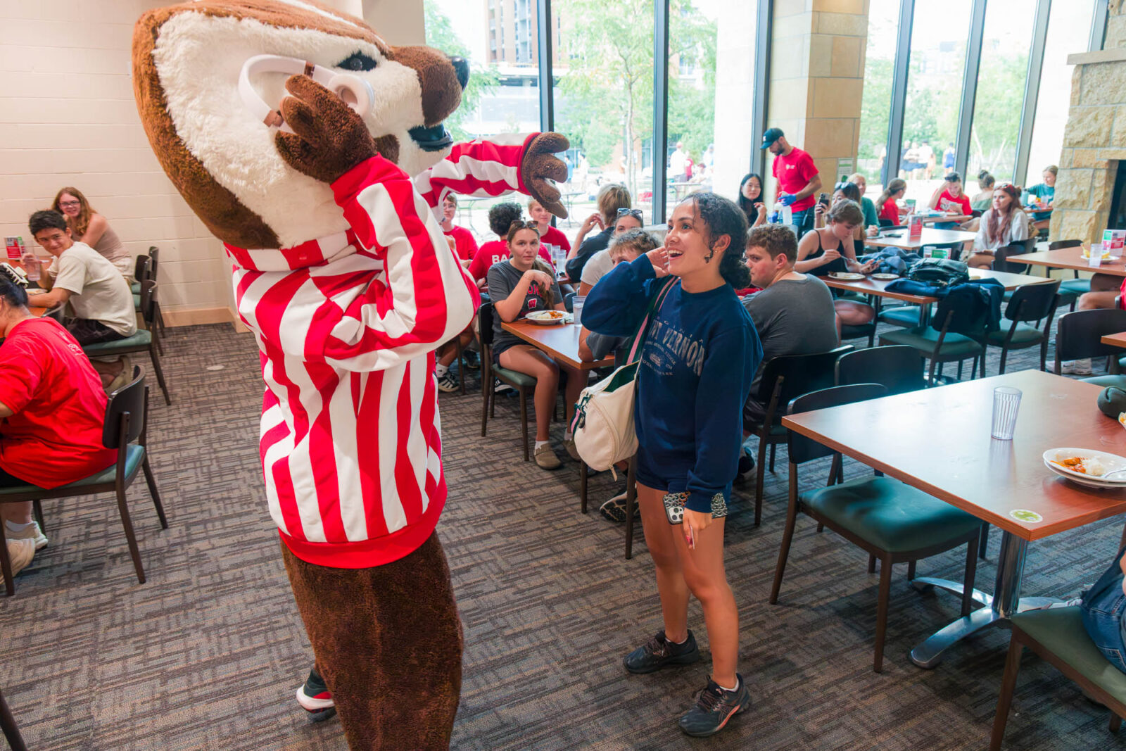 Bucky listens to a residents' headphones while the resident smiles in the Gordon Dining Room