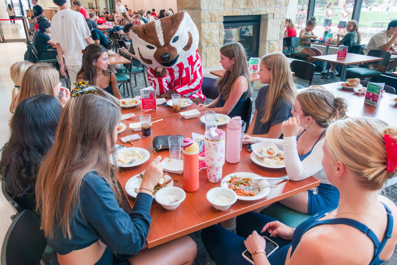 Bucky joins a group of students at a table at Gordon during the Badger Welcome Dinner