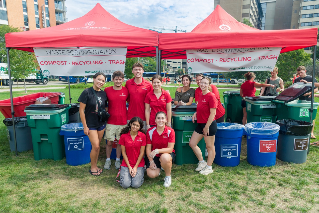 Student staff pose for photo by waste sorting station at Convocation Lunch