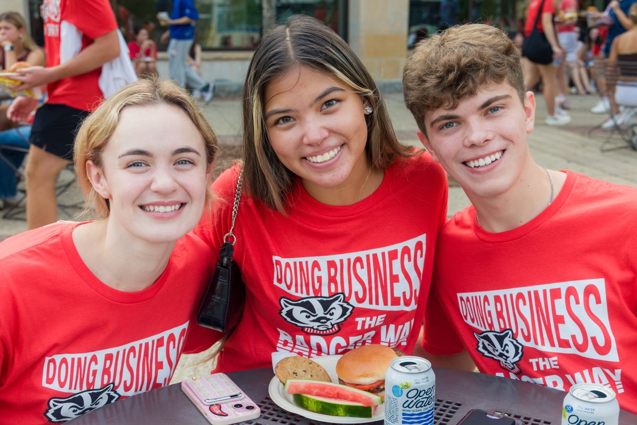 Three students pose for photo at table outside during Convocation Lunch