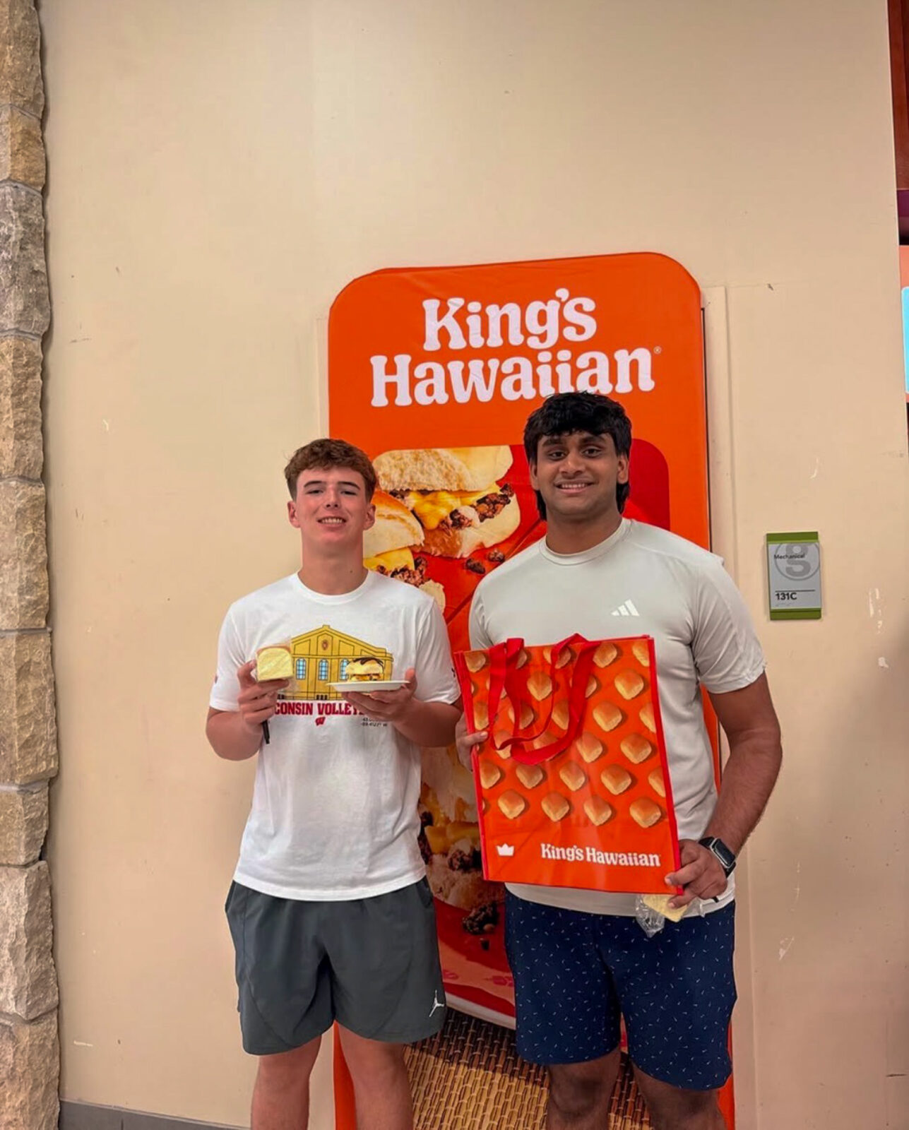 Two students pose for photo with King's Hawaiian swag and food at the grand opening