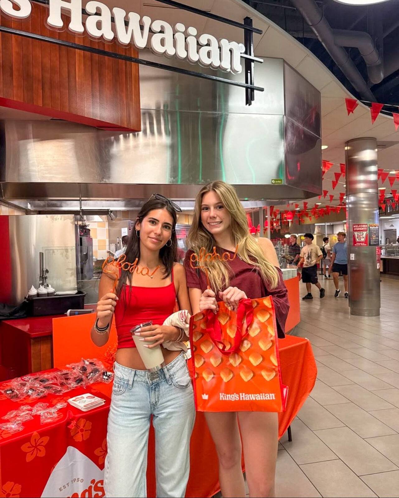 Two students pose for photo with King's Hawaiian swag at the grand opening